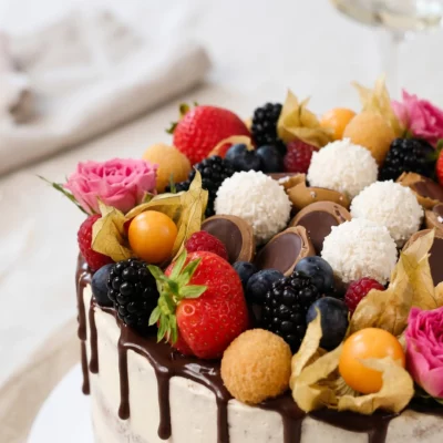 Detail ovocného dortu Raffaello a Toffifee s jahodami, ostružinami, borůvkami, malinami, physalis, kokosovými kuličkami a čokoládovým zdobením.