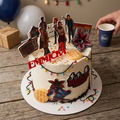 Šikmý pohled na dort Stranger Things s červeným zápichem, seriálovými postavami, vaflí a bočními dekoracemi.