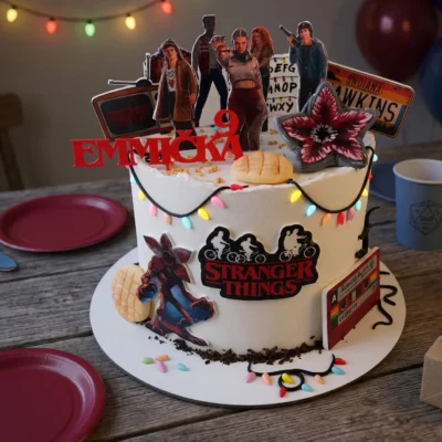 Dort Stranger Things v temnější narozeninové scéně se světelnou girlandou, balónky a retro seriálovou atmosférou.