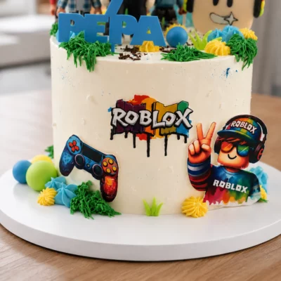 Čelní detail dortu Roblox s plochým herním motivem, obrázkem ovladače, postavičkou se sluchátky a barevným krémovým zdobením.
