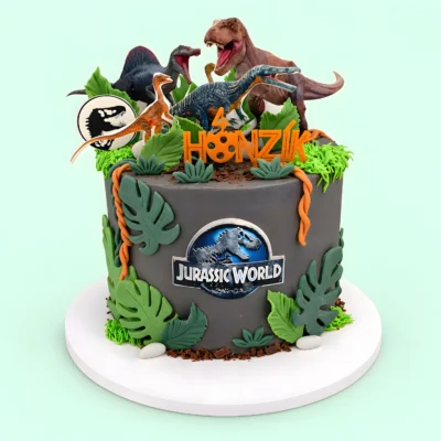Dort s obrázky dinosaurů nahoře, znakem Jurassic World vpředu, velkými zelenými listy, liánami a kamínkovými dekoracemi.